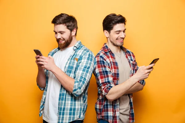 Portrait de deux jeunes hommes heureux utilisant des téléphones mobiles — Photo