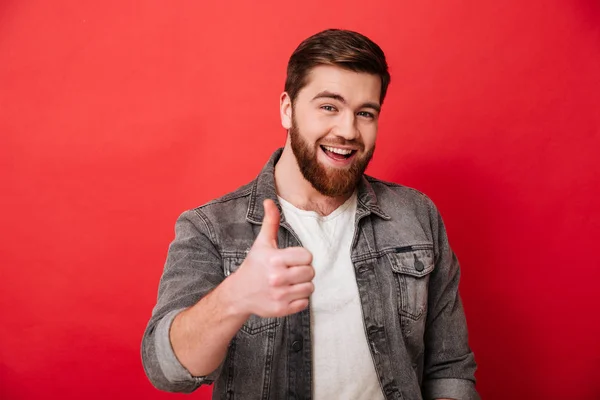 Foto av glada skäggiga killen 30s i jeans jacka leende och Visa — Stockfoto