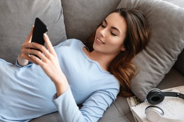 Cep telefonu kullaranarak gülümseyen bir genç kadın portresi
