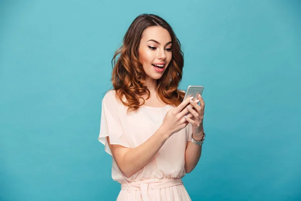 Imagen de la mujer alegre de 20 años sonriendo y usando el teléfono móvil mientras —  Fotos de Stock