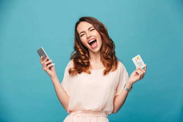 Jovencita gritando usando teléfono móvil sosteniendo tarjeta de crédito . — Foto de Stock