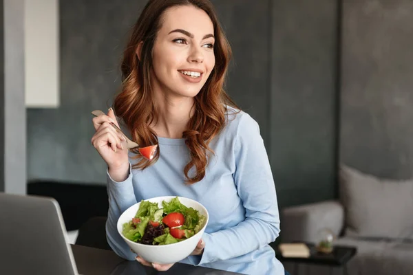 Portréja egy mosolygó fiatal nő eszik friss salátával — Stock Fotó