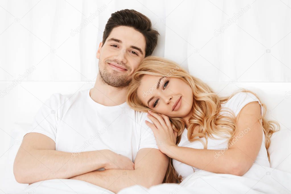 Loving couple lies in bed indoors at home