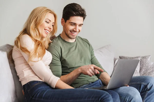노트북 컴퓨터를 사용 하 여 소파에 앉아 귀여운 젊은 사랑 하는 커플. — 스톡 사진