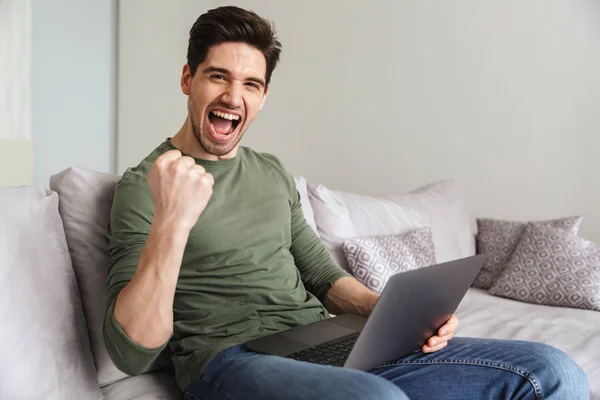 Zadowolony młody człowiek za pomocą komputera przenośnego — Zdjęcie stockowe