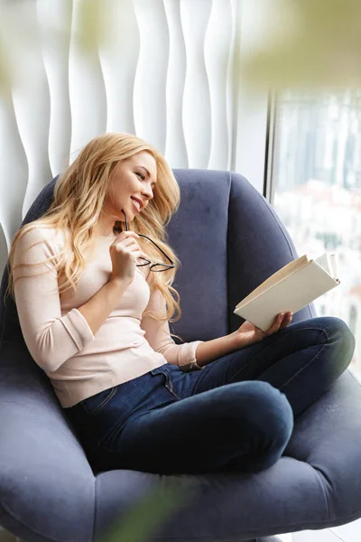 Souriant jeune femme à l'intérieur à la maison livre de lecture — Photo