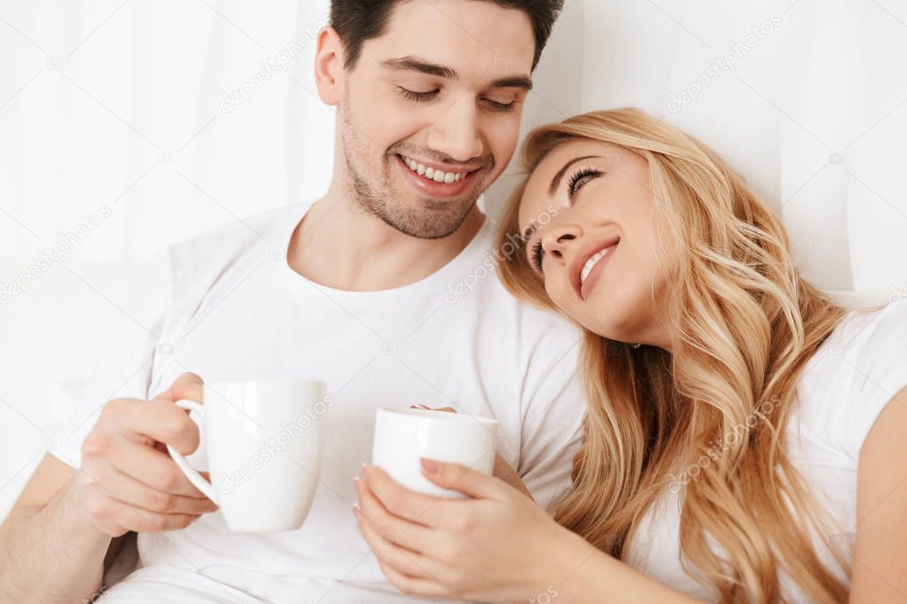 Happy loving couple in bed indoors at home