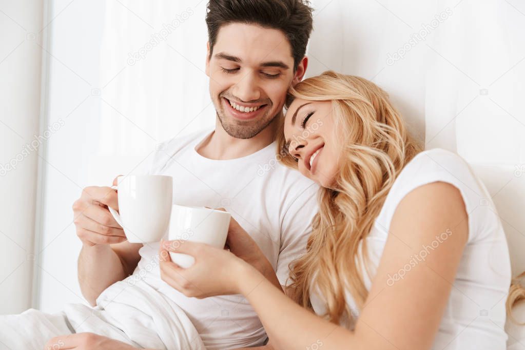 Happy loving couple in bed indoors at home
