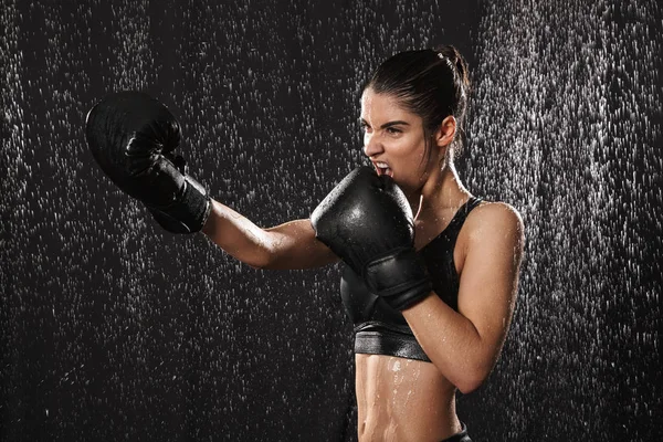 Mujer femenina luchadora de 20 años en ropa deportiva y guantes de boxeo negros — Foto de Stock