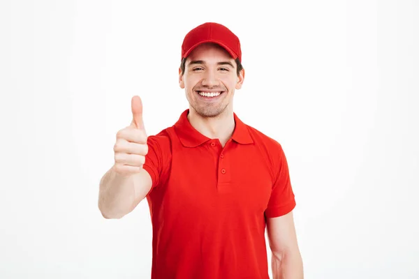 Joven y alegre repartidor en gorra roja con los pulgares arriba — Foto de Stock