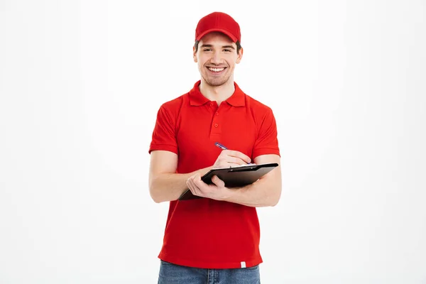 Retrato de homem de entrega sorridente em t-shirt vermelha e boné olhando — Fotografia de Stock