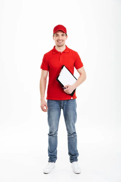 Imagem de comprimento total do jovem mensageiro homem 20s em uniforme vermelho e je — Fotografia de Stock