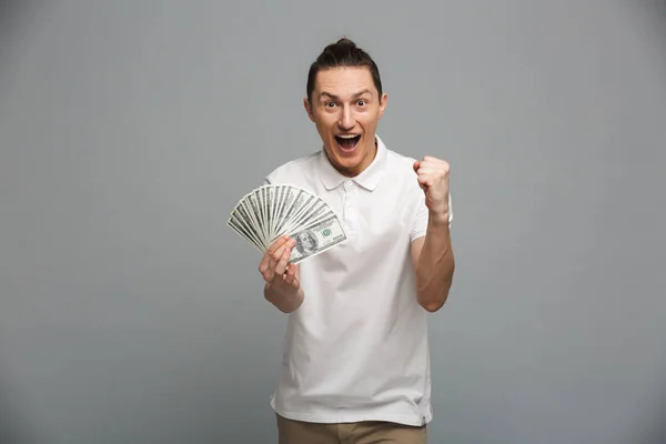 Chocado gritando jovem segurando dinheiro fazer gesto vencedor . — Fotografia de Stock