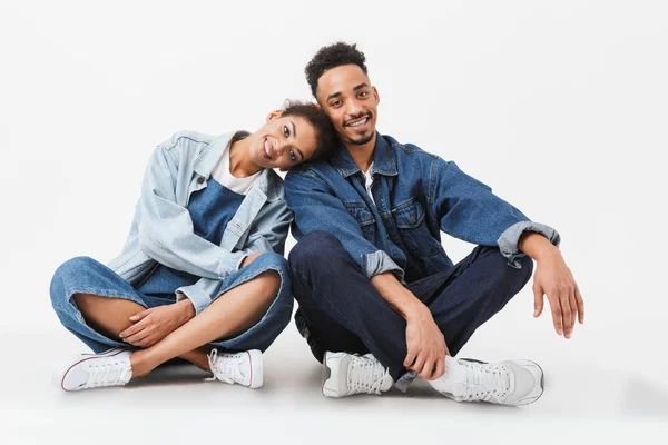 Lächelndes afrikanisches Paar in Jeanshemden, das zusammen auf dem Boden sitzt — Stockfoto