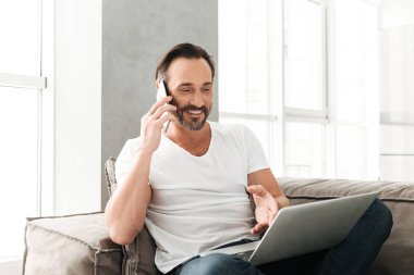 Gülümseyen olgun bir adam cep telefonuyla konuşuyor.