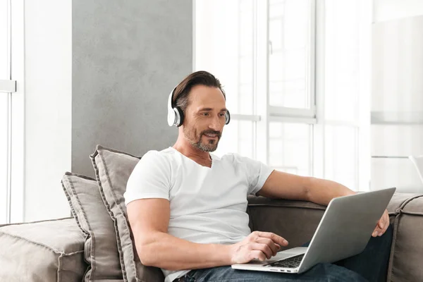 Sonriente hombre maduro escuchando música con auriculares — Foto de Stock