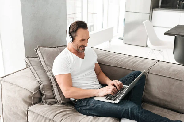 Tevreden volwassen man, luisteren naar muziek met koptelefoon — Stockfoto