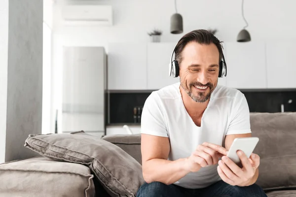 Sonriente hombre maduro escuchando música con auriculares — Foto de Stock