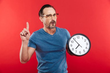 Yetişkin ciddi adam tutarak saat.