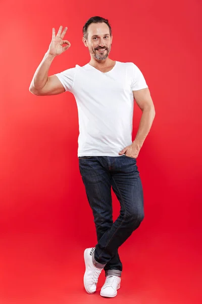 Cheerful adult man standing isolated showing okay gesture. — Stock Photo, Image