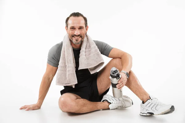 Portrait of a smiling mature sportsman drinking water — Stock Photo, Image