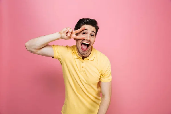 Portrait of a smiling young man showing peace gesture — Stock Photo, Image