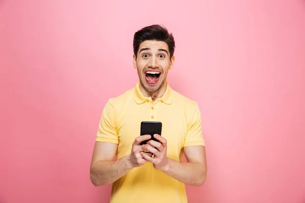 Retrato de un joven emocionado sosteniendo el teléfono móvil — Foto de Stock