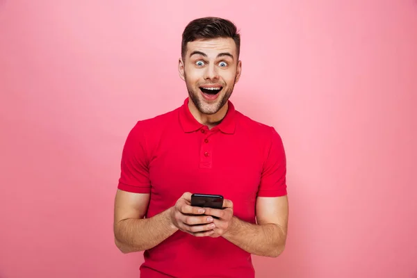 Retrato de un joven emocionado sosteniendo el teléfono móvil — Foto de Stock