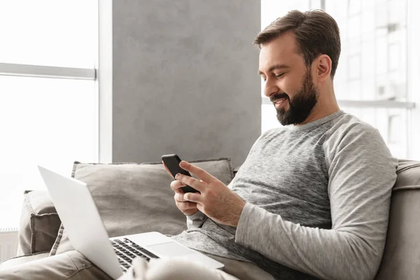 Imagen de hombre caucásico 30s en ropa casual sentado en sofá en liv — Foto de Stock