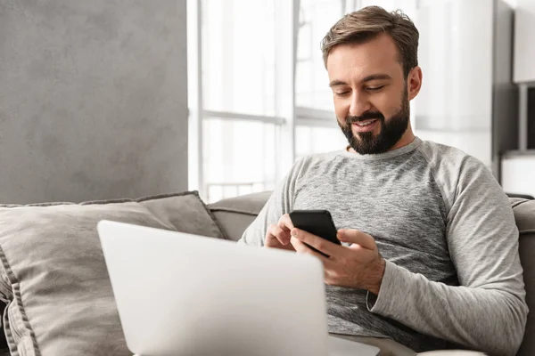 Foto do homem caucasiano dos anos 30 em uso casual usando smartphone, enquanto — Fotografia de Stock