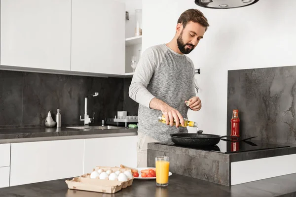 Stilig ungkarl med kort brunt hår och skägg matlagning omelett — Stockfoto