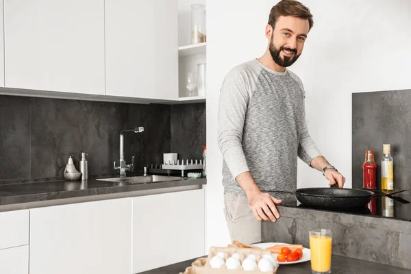 Single happy man wearing casual clothing cooking dinner on fryin — Stock Photo, Image