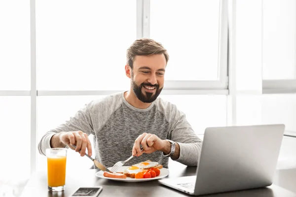 Unshaved satisfeito homem 30 anos vestindo roupas casuais comer frito — Fotografia de Stock