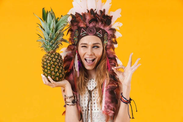 Porträt einer entzückten Frau mit Federkleid, Ananas in der Hand und gestikulierendem Ok-Zeichen — Stockfoto