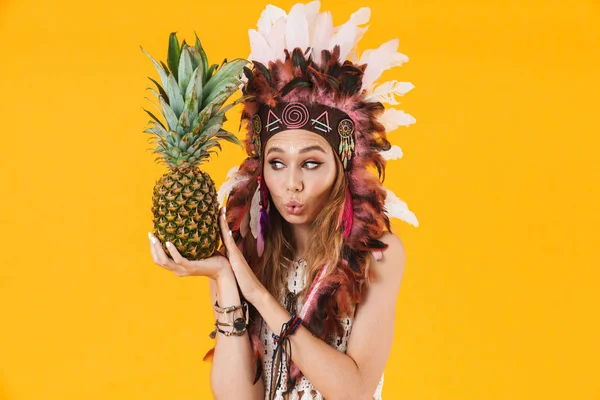 Porträt einer lustigen Frau mit Federkopfschmuck mit Ananas und Grimassen — Stockfoto