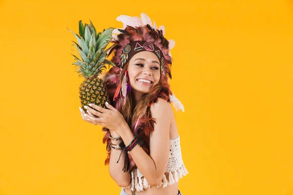 Porträt einer süßen Frau mit Federkopfschmuck, die Ananas hält und lächelt — Stockfoto