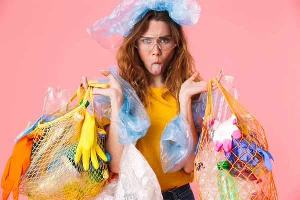 Фото женщины, держащей мешки с пластиковыми отходами и засовывающей язык — стоковое фото