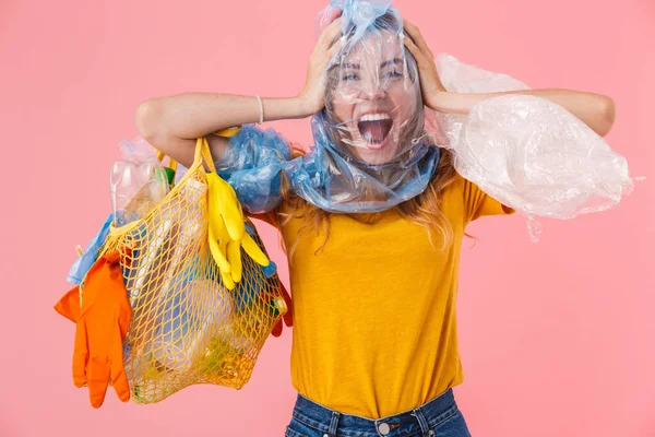 Foto de mujer nerviosa con paquete en la cabeza sosteniendo residuos de plástico —  Fotos de Stock