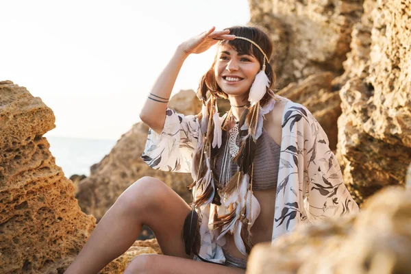 Imagen de una chica hippy sonriente con diadema de plumas sentada cerca — Foto de Stock