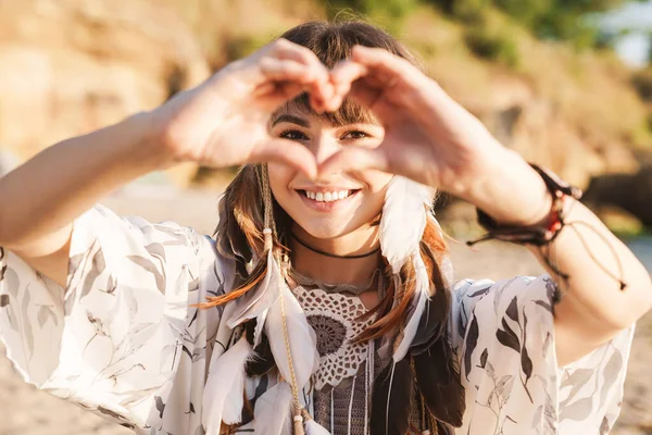 Image de la fille hippie dans le bandeau de plumes montrant la forme du cœur par s — Photo