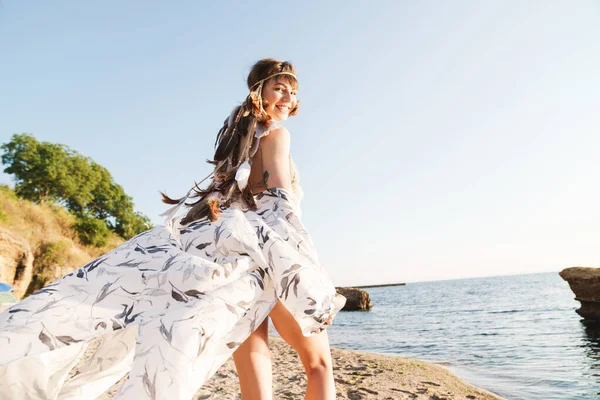 Image de hippie fille portant bandeau de plumes marchant au bord de la mer — Photo