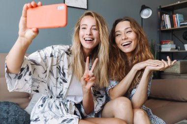 Evde cep telefonu kullanan iyimser kadınlar selfie çeker..