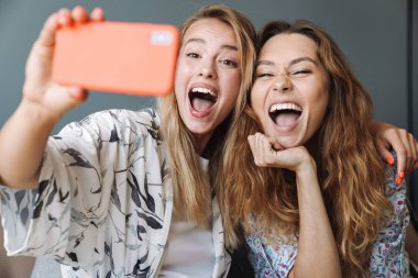 Evde cep telefonu kullanan iyimser kadınlar selfie çeker..