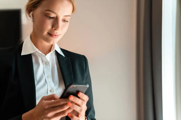 Zakelijke vrouw met behulp van mobiele telefoon luisteren muziek — Stockfoto