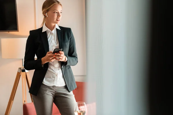 Mujer de negocios en interiores usando el teléfono móvil escuchando música —  Fotos de Stock