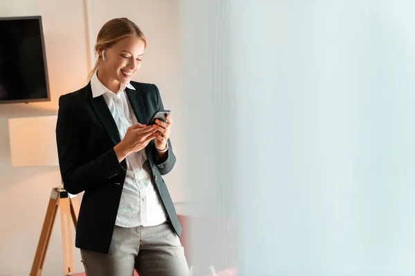 Business woman indoors using mobile phone listening music — Stock Photo, Image