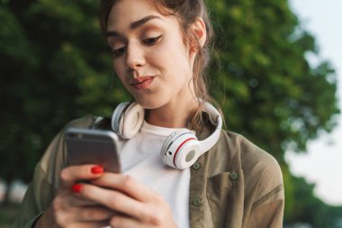 Akıllı telefonu tutan ve açgözlülükle yürüyen çekici bir kadın.