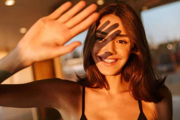 Bild einer fröhlichen Frau, die ihr Gesicht vor Sonnenschein mit der Hand bedeckt — Stockfoto