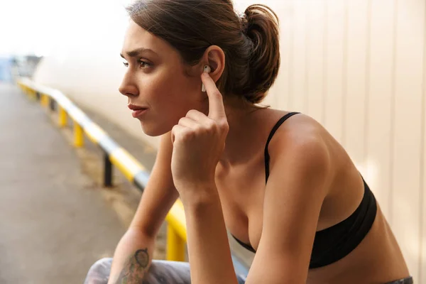 Image of charming young woman listening music with earpod