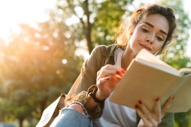 Green Park 'ta gülümseyen ve kitap okuyan genç bir kadın resmi